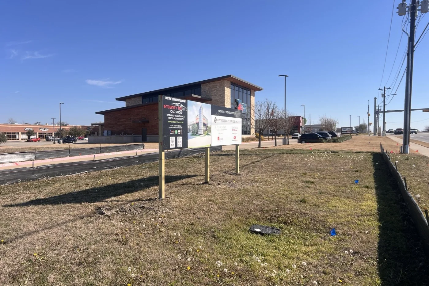 The Anna site in February 2026: an empty grass lot on Victoria Falls Drive with a development sign at the roadside.