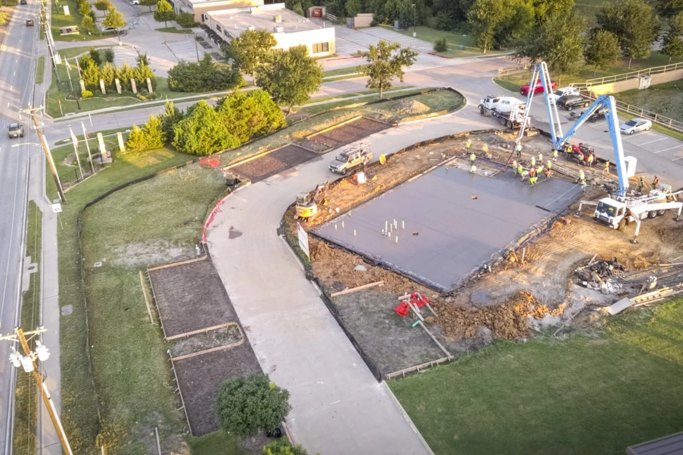 Aerial view of the slab pour at the Anna site in July 2026, with concrete pump trucks and crew working across the poured deck.