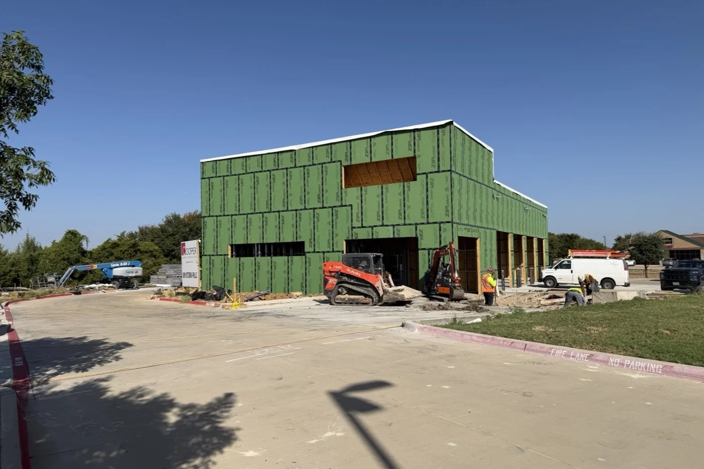 The Anna facility in September 2026, wrapped in green sheathing with the parking lot poured and marked.
