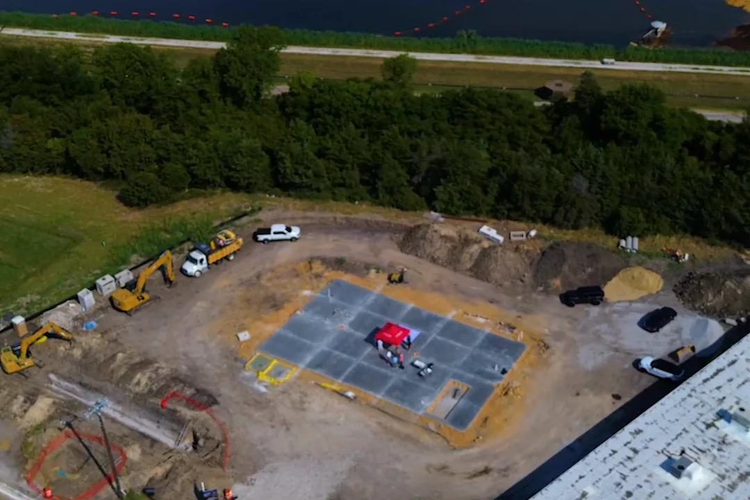 Wide aerial of the Wylie site in context, showing the detention pond, the highway and neighbouring commercial buildings.