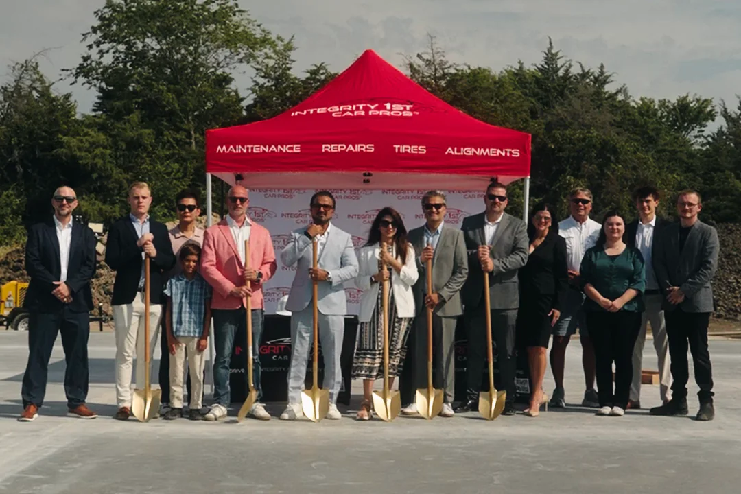 The groundbreaking ceremony at the Wylie site, with attendees holding ceremonial shovels on the poured slab.