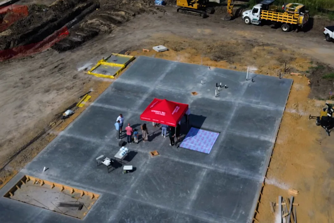Aerial view of the poured concrete slab at the Wylie, Texas site, with excavators and a haul truck at its edge.