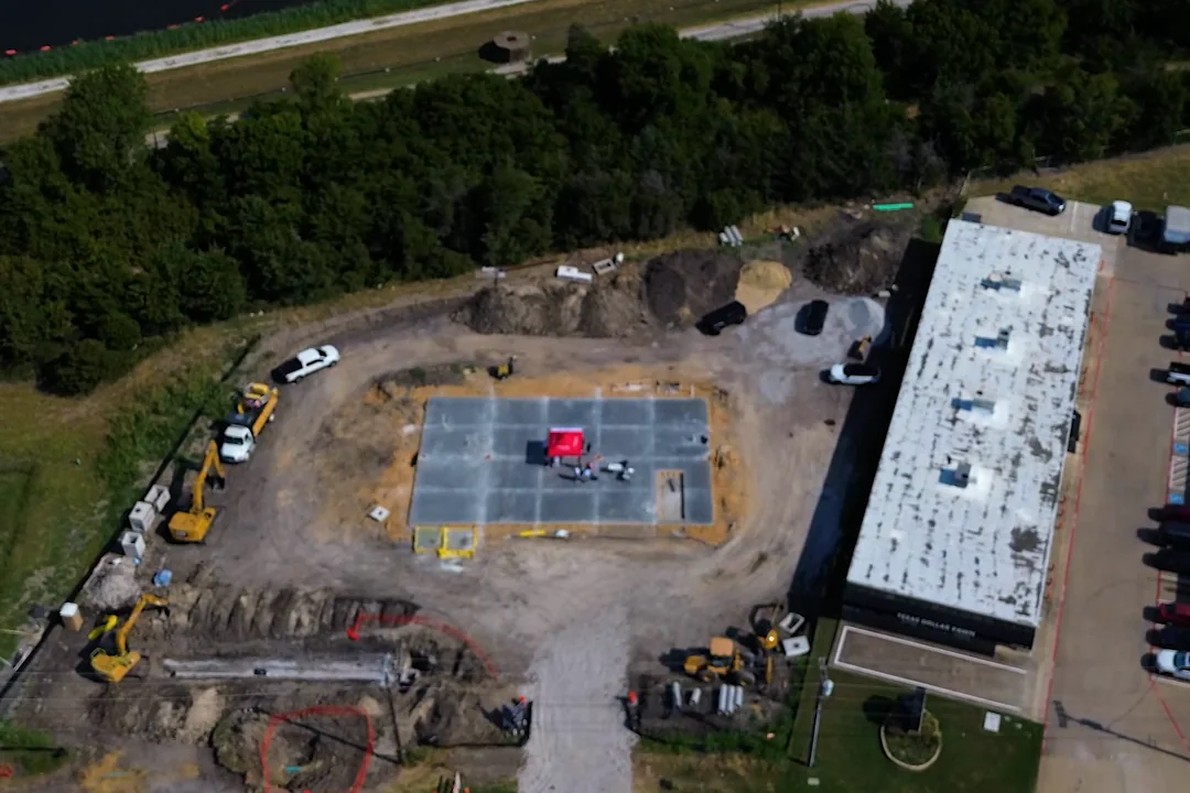 Aerial view of the Wylie site with tracked excavators, haul trucks and open trenching alongside the slab.